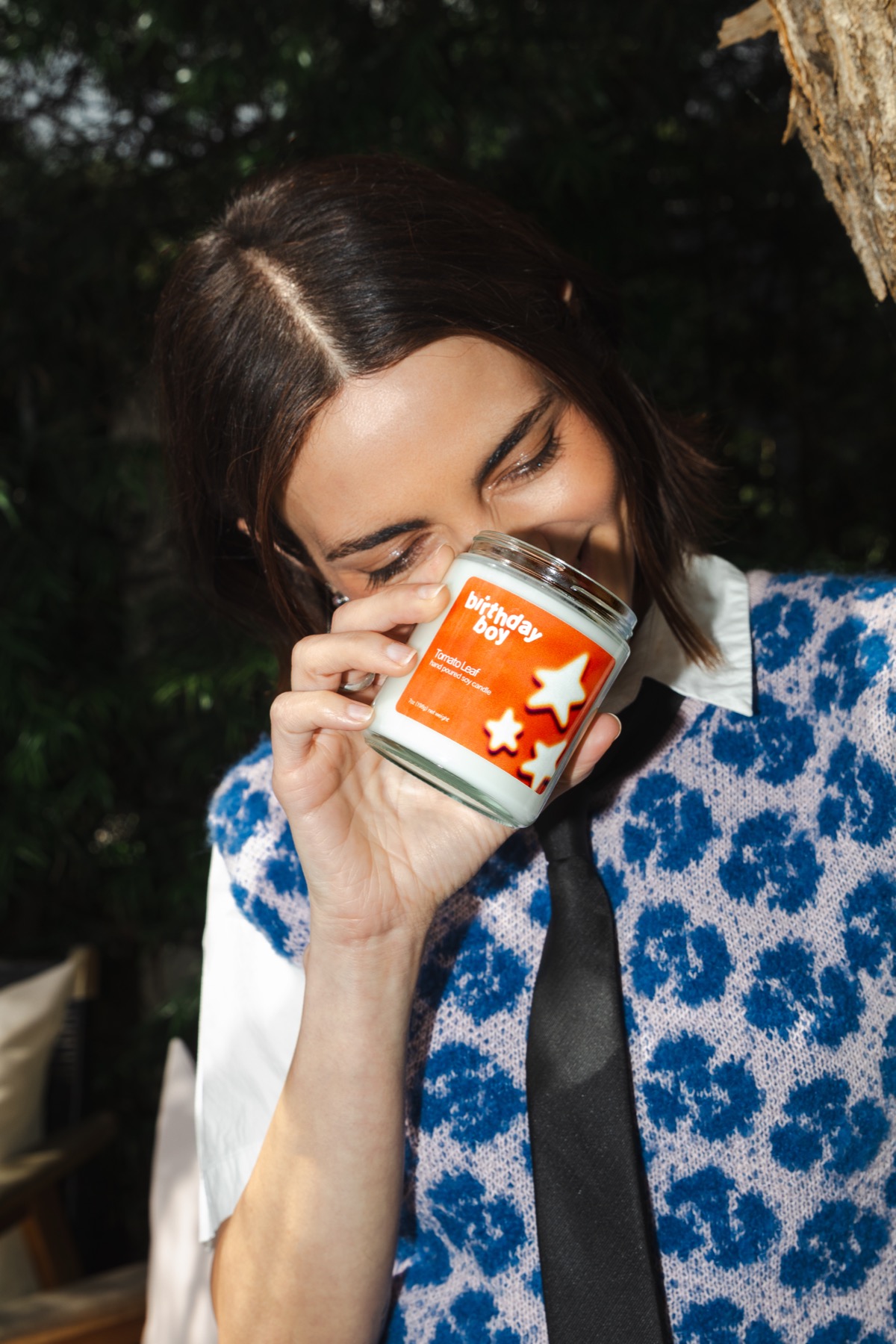 Close-up of a woman smelling a Birthday Boy Tomato Leaf candle