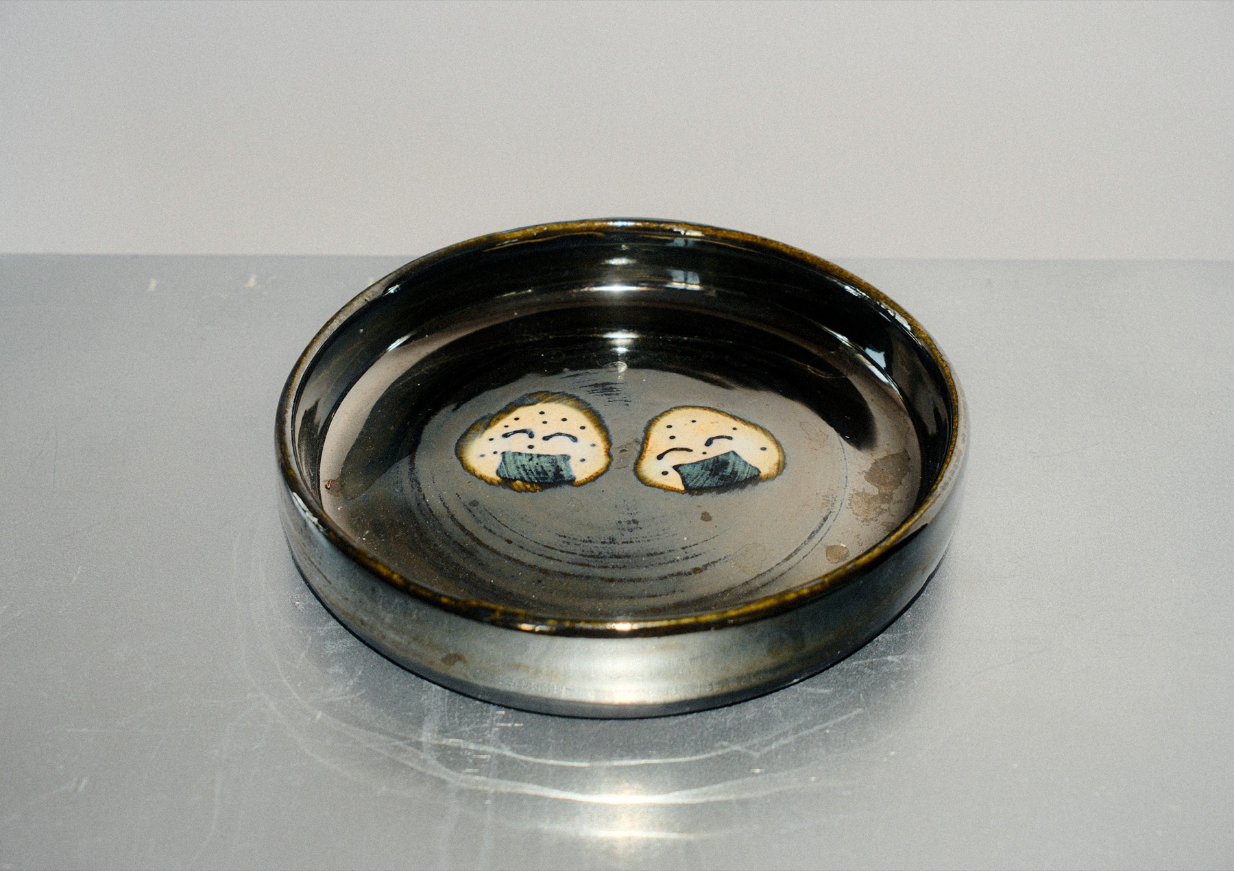 Dark round dish hand-painted with two onigiri characters
